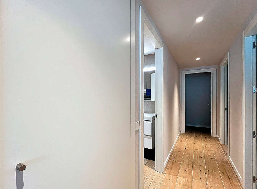 Step into this beautifully designed hallway, showcasing a modern aesthetic with its sleek white doors and warm wooden flooring.