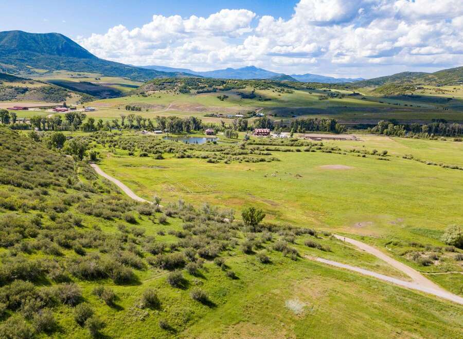 Discover the tranquility of this stunning property, featuring expansive green pastures and rolling hills.