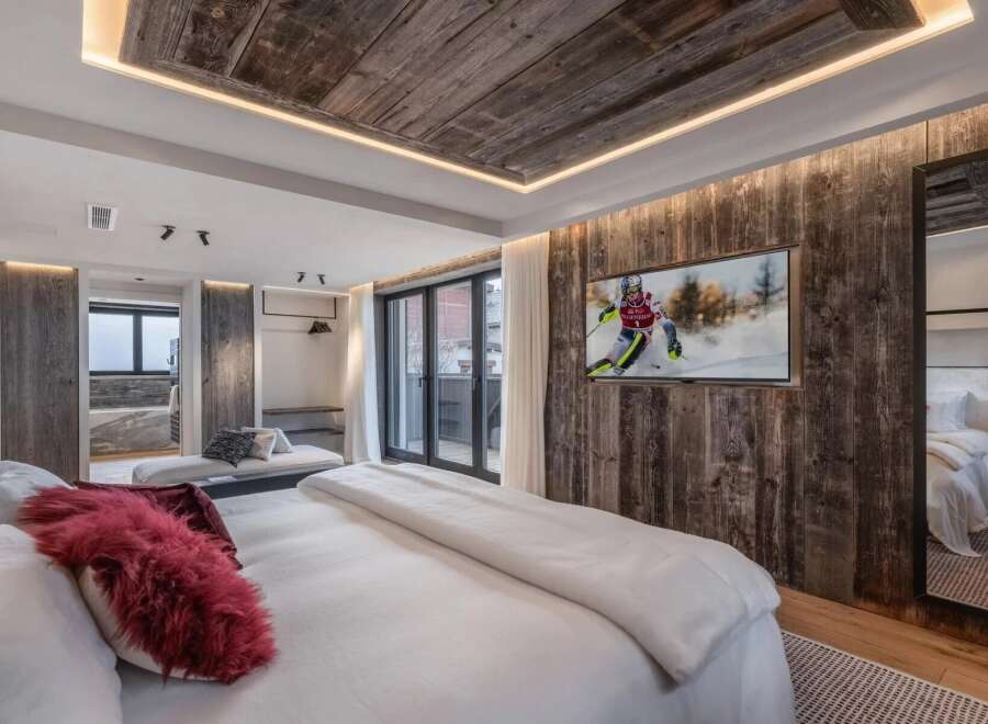 Experience luxury living in this stunning bedroom, featuring a rustic wood-paneled accent wall and a cozy, inviting atmosphere.