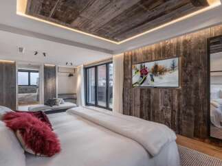 Experience luxury living in this stunning bedroom, featuring a rustic wood-paneled accent wall and a cozy, inviting atmosphere.
