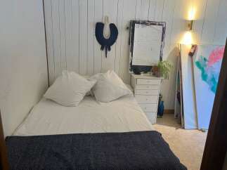 This cozy bedroom features a comfortable bed with soft pillows and a stylish navy throw.