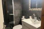 This modern bathroom features sleek, dark gray tiles and a glass shower enclosure, creating a sophisticated and contemporary feel.
