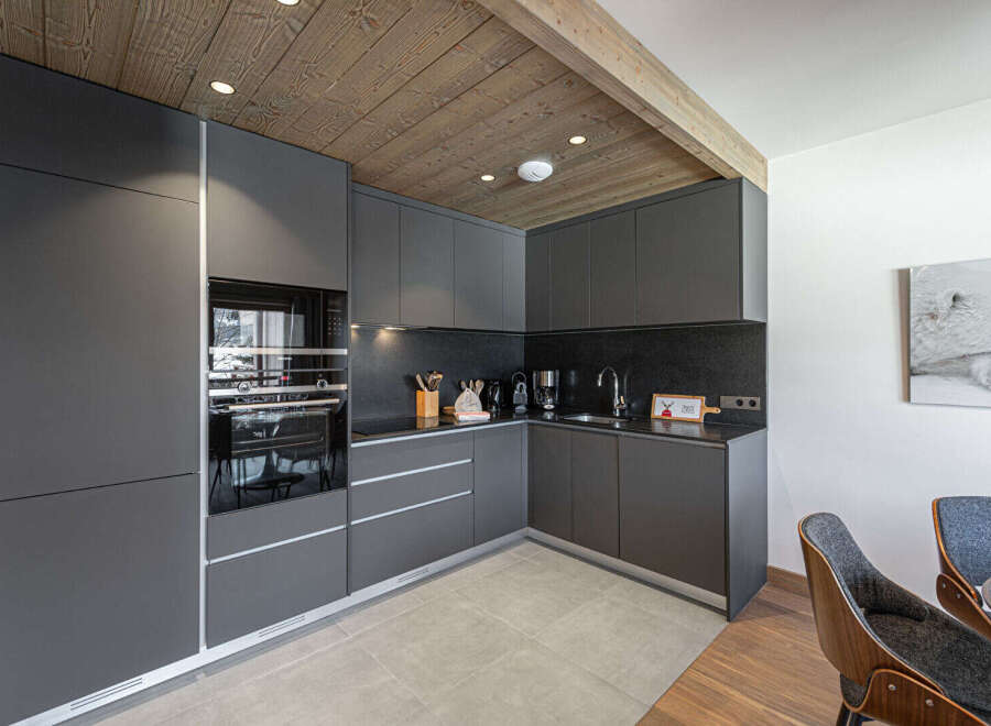 Discover modern luxury in this stunning kitchen! Featuring sleek, dark cabinetry, a built-in oven, and a stylish countertop, this space is perfect for culinary enthusiasts.
