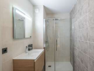 Step into this modern bathroom, featuring a sleek glass shower enclosure and stylish vanity.