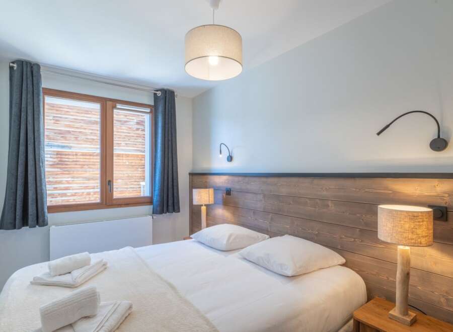 This cozy bedroom features a comfortable bed with crisp white linens and plush pillows, perfect for a relaxing stay.