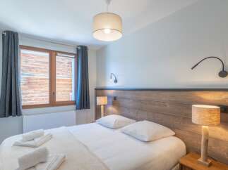 This cozy bedroom features a comfortable bed with crisp white linens and plush pillows, perfect for a relaxing stay.