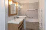 This inviting bathroom features a stylish wooden vanity with a sleek white sink, offering ample storage space.