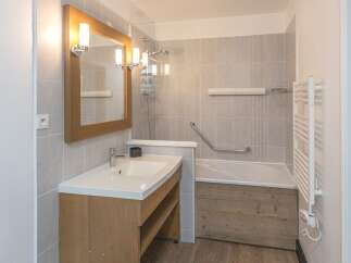 This inviting bathroom features a stylish wooden vanity with a sleek white sink, offering ample storage space.