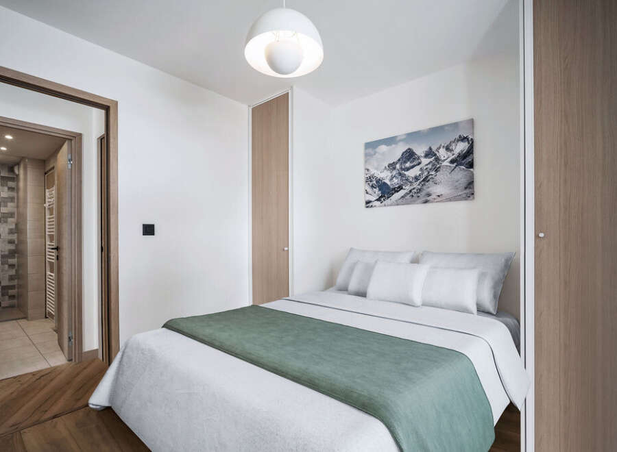 This cozy bedroom features a comfortable bed with soft bedding and a stylish green throw.