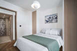 This cozy bedroom features a comfortable bed with soft bedding and a stylish green throw.