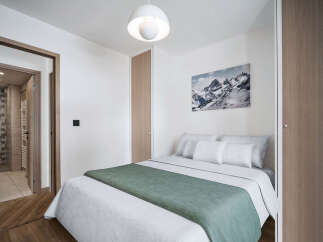 This cozy bedroom features a comfortable bed with soft bedding and a stylish green throw.