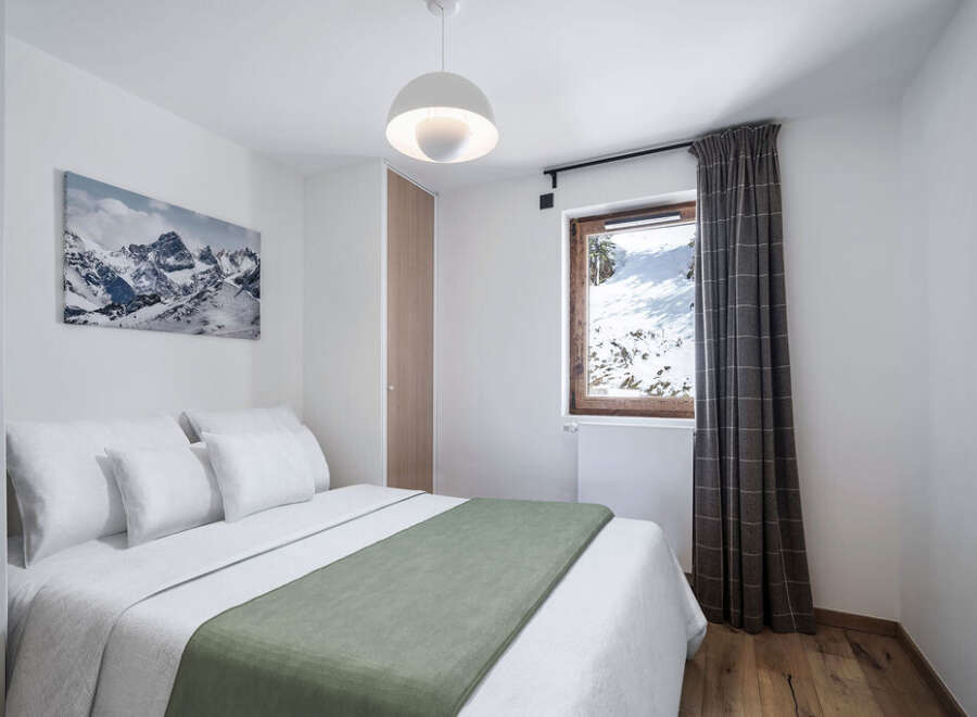 This cozy bedroom offers a serene retreat with stunning mountain views visible through the window.