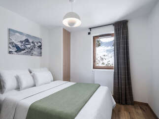 This cozy bedroom offers a serene retreat with stunning mountain views visible through the window.