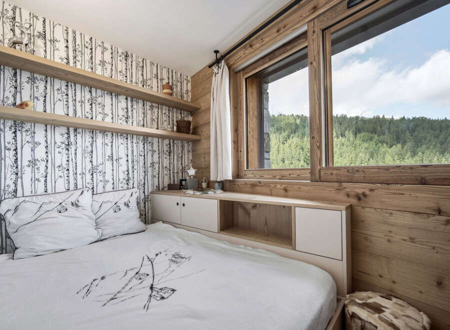 This cozy bedroom features a unique birch tree wallpaper and wooden accents, creating a warm and inviting atmosphere.