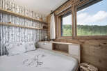 This cozy bedroom features a unique birch tree wallpaper and wooden accents, creating a warm and inviting atmosphere.