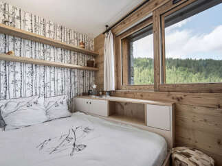 This cozy bedroom features a unique birch tree wallpaper and wooden accents, creating a warm and inviting atmosphere.
