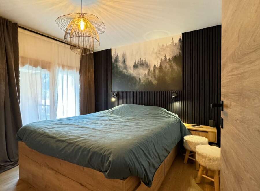 This cozy bedroom features a stylish design with a unique forest-themed wall art, creating a serene atmosphere.