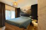 This cozy bedroom features a stylish design with a unique forest-themed wall art, creating a serene atmosphere.