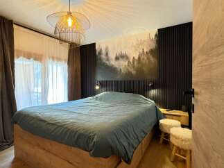 This cozy bedroom features a stylish design with a unique forest-themed wall art, creating a serene atmosphere.