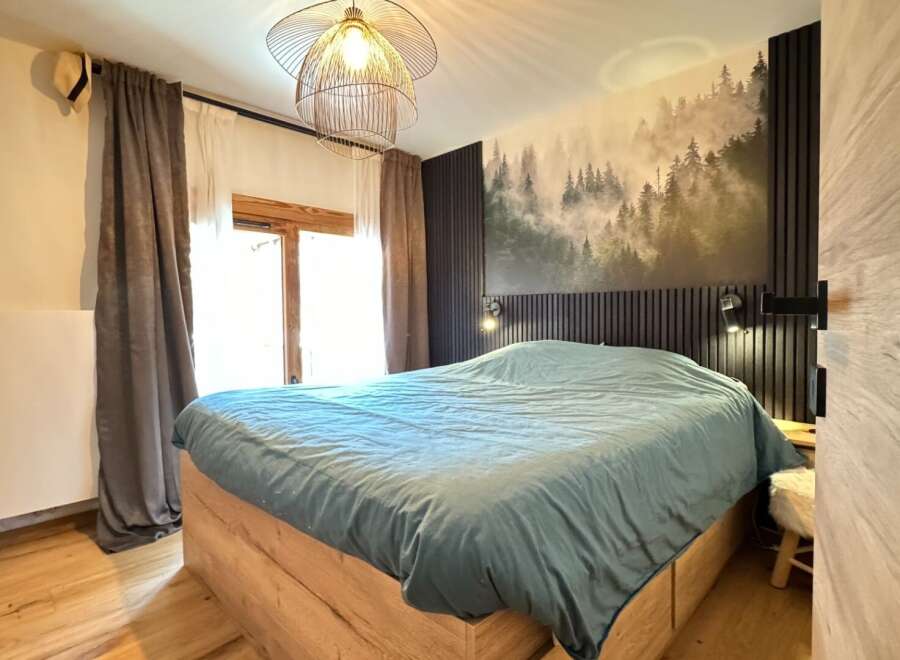 This cozy bedroom features a stunning forest-themed accent wall, creating a serene and inviting atmosphere.