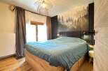 This cozy bedroom features a stunning forest-themed accent wall, creating a serene and inviting atmosphere.