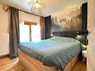 This cozy bedroom features a stunning forest-themed accent wall, creating a serene and inviting atmosphere.