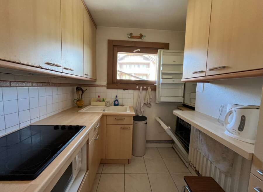 This charming kitchen features a modern cooktop, ample cabinet space, and a convenient sink area.