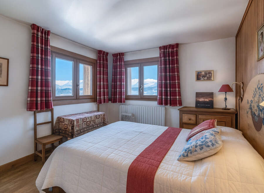 Experience the charm of this cozy bedroom, featuring stunning mountain views through the windows.