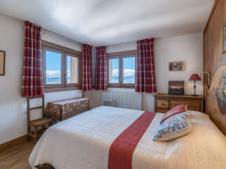 Experience the charm of this cozy bedroom, featuring stunning mountain views through the windows.