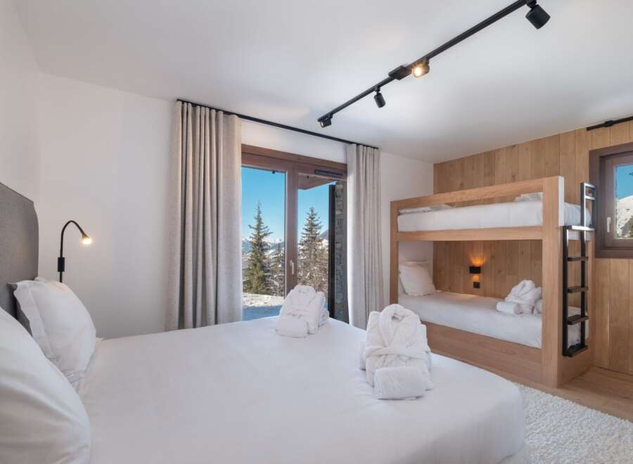 Experience luxury in this stunning bedroom featuring a cozy bunk bed and a comfortable king-size bed.