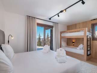 Experience luxury in this stunning bedroom featuring a cozy bunk bed and a comfortable king-size bed.