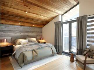 This stunning bedroom boasts a rustic charm with its wooden ceiling and accent wall, creating a warm and inviting atmosphere.
