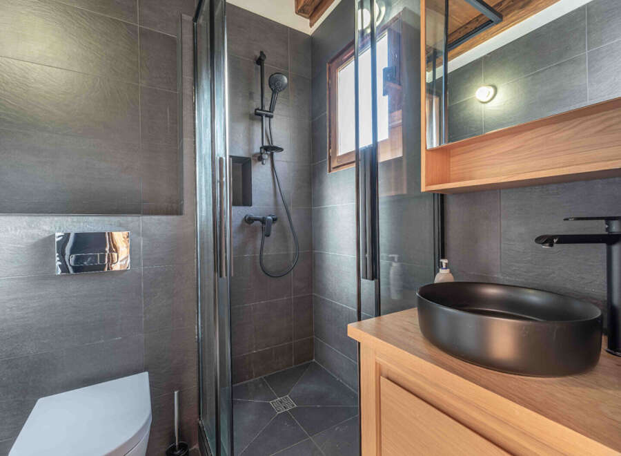 Step into this modern bathroom, featuring sleek gray tiles and a stylish black sink.