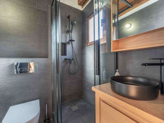 Step into this modern bathroom, featuring sleek gray tiles and a stylish black sink.