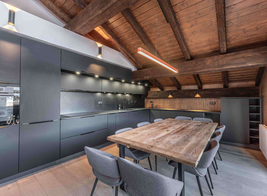This stunning kitchen and dining area boasts a rustic charm with its exposed wooden beams and a large, inviting dining table.