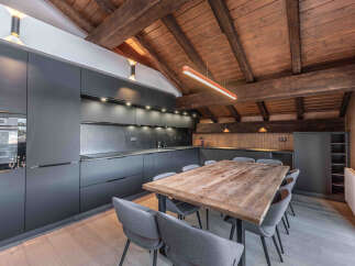 This stunning kitchen and dining area boasts a rustic charm with its exposed wooden beams and a large, inviting dining table.