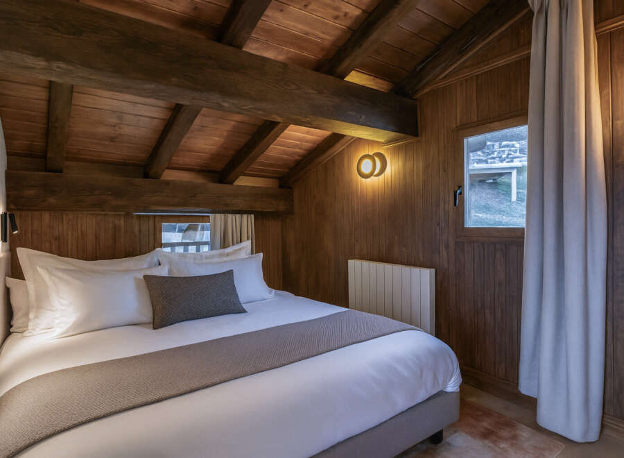 Experience rustic charm in this cozy bedroom featuring a wooden ceiling and walls, creating a warm and inviting atmosphere.