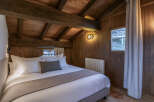 Experience rustic charm in this cozy bedroom featuring a wooden ceiling and walls, creating a warm and inviting atmosphere.