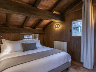 Experience rustic charm in this cozy bedroom featuring a wooden ceiling and walls, creating a warm and inviting atmosphere.