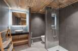 This modern bathroom features a sleek design with a wooden ceiling and gray tiled walls.