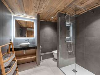 This modern bathroom features a sleek design with a wooden ceiling and gray tiled walls.