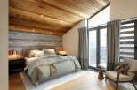 This stunning bedroom boasts a rustic charm with its wooden ceiling and accent wall, creating a warm and inviting atmosphere.
