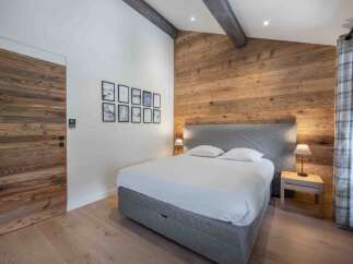 This stunning bedroom boasts a rustic charm with its wooden accent wall and exposed beams, creating a warm and inviting atmosphere.