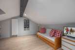 This cozy attic space features a comfortable wooden daybed with red plaid pillows, perfect for relaxing.