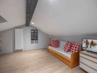 This cozy attic space features a comfortable wooden daybed with red plaid pillows, perfect for relaxing.