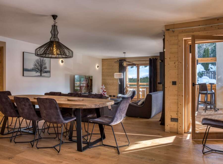 This stunning property boasts a spacious dining area with a large wooden table and stylish chairs, perfect for entertaining guests.