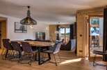 This stunning property boasts a spacious dining area with a large wooden table and stylish chairs, perfect for entertaining guests.