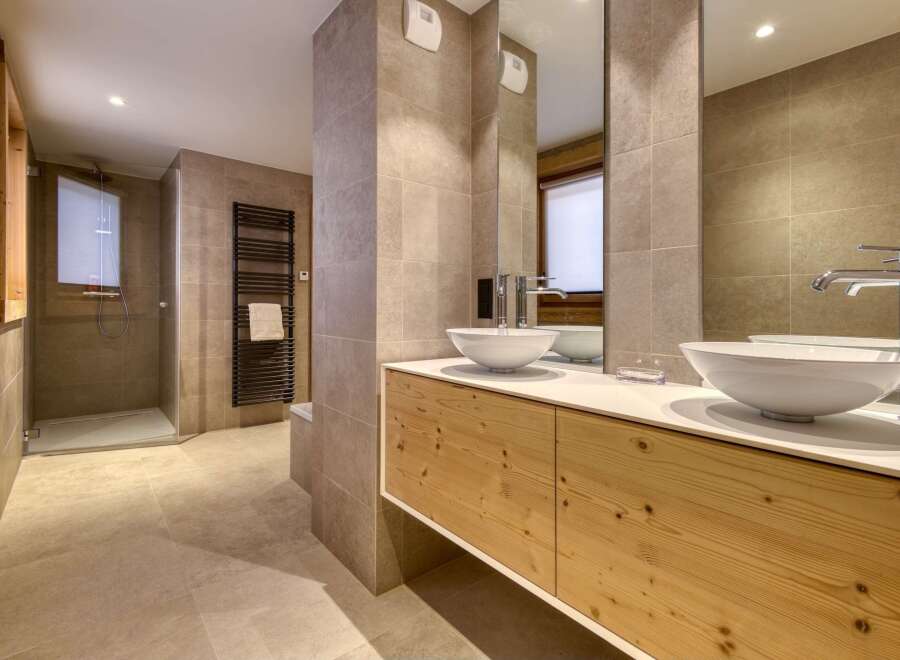 This luxurious bathroom features a modern design with a sleek vanity and two stylish sinks.