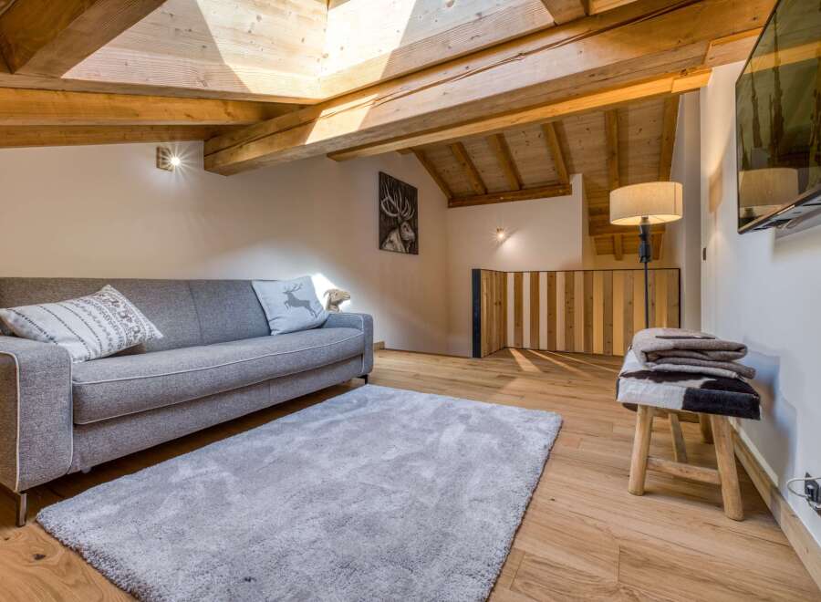 This cozy living space features a modern gray sofa, a plush rug, and a unique wooden ceiling.