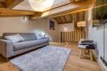 This cozy living space features a modern gray sofa, a plush rug, and a unique wooden ceiling.